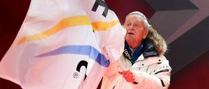 Gian Franco Kasper, der FIS-Präsident, versucht, mit der FIS-Fahne zu wedeln.