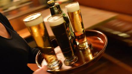 ARCHIV - Eine Bedienung trägt am 29.10.2013 in Erfurt (Thüringen) in einem Lokal ein Tablett mit Bier. Die standortfeste Gastronomie hat die steuerliche Gleichbehandlung mit anderen Branchen-Unternehmen wie Caterern gefordert. (zu dpa "Dehoga fordert faire Steuersätze für Gastronomie-Betriebe" vom 25.12.2016) Foto: Marc Tirl/dpa-Zentralbild/dpa +++(c) dpa - Bildfunk+++