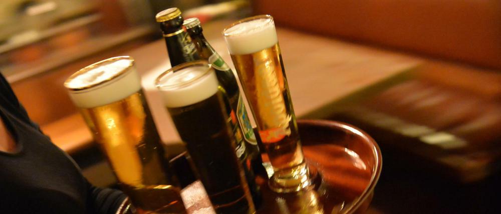 ARCHIV - Eine Bedienung trägt am 29.10.2013 in Erfurt (Thüringen) in einem Lokal ein Tablett mit Bier. Die standortfeste Gastronomie hat die steuerliche Gleichbehandlung mit anderen Branchen-Unternehmen wie Caterern gefordert. (zu dpa "Dehoga fordert faire Steuersätze für Gastronomie-Betriebe" vom 25.12.2016) Foto: Marc Tirl/dpa-Zentralbild/dpa +++(c) dpa - Bildfunk+++