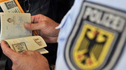 Ein Beamter der Bundespolizei kontrolliert am Frankfurter Flughafen einen Pass.
