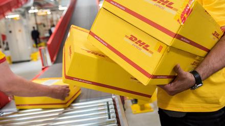 Mitarbeiter des Logistikunternehmens Deutsche Post DHL legen (hier in Hamburg) in einer Express-Station Pakete auf ein Laufband. 