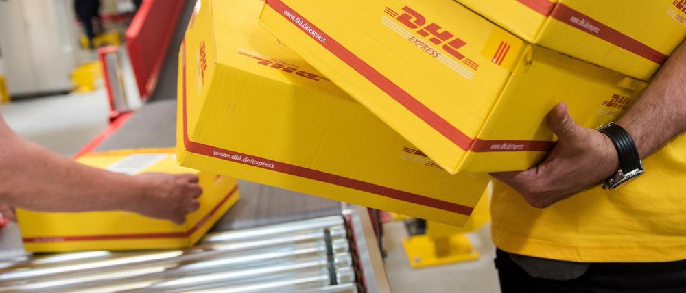 Mitarbeiter des Logistikunternehmens Deutsche Post DHL legen (hier in Hamburg) in einer Express-Station Pakete auf ein Laufband.
