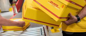 Mitarbeiter des Logistikunternehmens Deutsche Post DHL legen (hier in Hamburg) in einer Express-Station Pakete auf ein Laufband. 