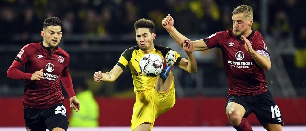 Hoch das Bein. Dortmunds Raphael Guerreiro wird von den beiden Nürnbergern Hanno Behrens (r.) und Tim Leibold bedrängt.