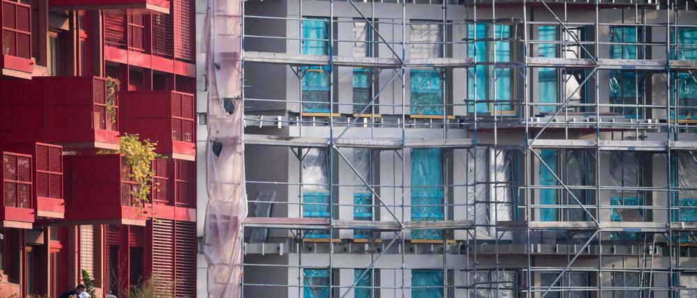 Ein Baugerüst steht an einem Rohbau neben bereits fertiggestellten Neubau-Wohnungen in Kreuzberg.