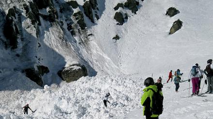 Rettungskräfte suchen im Lawinengebiet neben der Piste nach Verschütteten.