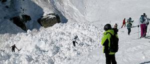 Rettungskräfte suchen im Lawinengebiet neben der Piste nach Verschütteten.