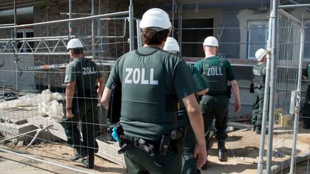 Zollbeamte betreten bei einer Razzia gegen Schwarzarbeit eine Baustelle. 