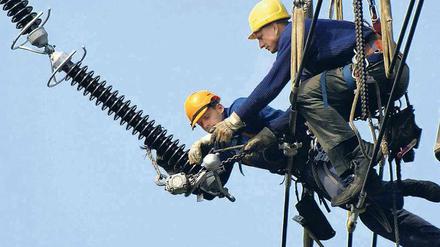 Vattenfall-Monteure machen sich auf dem Archivfoto an einer Hochspannungsleitung zu schaffen. Das Hochspannungsnetz hat der Konzern auf Druck der Politik längst verkauft, jetzt geht es um das 35 000 Kilometer lange Verteilnetz in Berlin. 