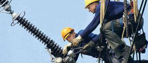 Vattenfall-Monteure machen sich auf dem Archivfoto an einer Hochspannungsleitung zu schaffen. Das Hochspannungsnetz hat der Konzern auf Druck der Politik längst verkauft, jetzt geht es um das 35 000 Kilometer lange Verteilnetz in Berlin. 