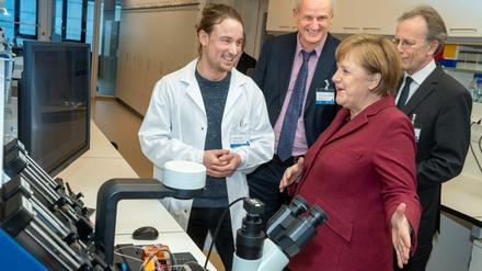 Jonathan Alles, Doktorand am BIMSB, Forschungsleiter Nikolaus Rajewsky und MDC-Vorstand Martin Lohse (vlnr) präsentieren Bundeskanzlerin Angela Merkel die Apparatur, mit der das Erbgut von Millionen von Zellen eines Organs Zelle für Zelle untersucht werden kann.