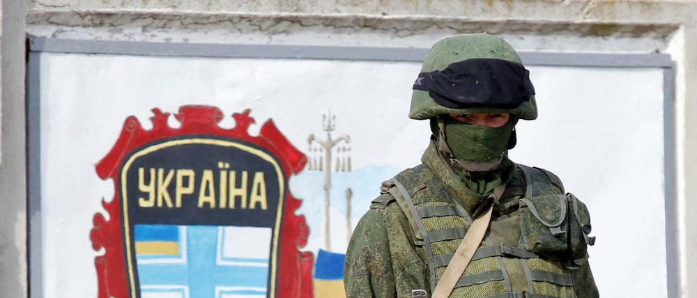 Ein Soldat in einer Uniform ohne Hoheitszeichen bewacht Anfang März 2014 eine ukrainische Militärbasis auf der Krim. 