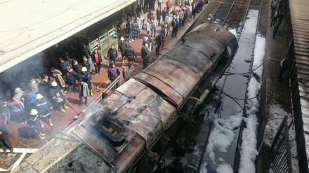 Rettungskräfte stehen neben einem ausgebrannten Waggon im Bahnhof in Kairo.