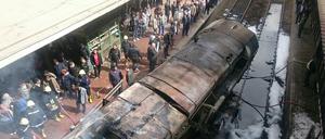 Rettungskräfte stehen neben einem ausgebrannten Waggon im Bahnhof in Kairo.