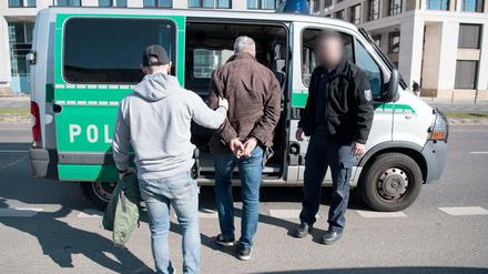 Polizeibeamte in Zivil führen einen Hütchenspieler an der East Side Gallery zu einem Polizeiwagen.