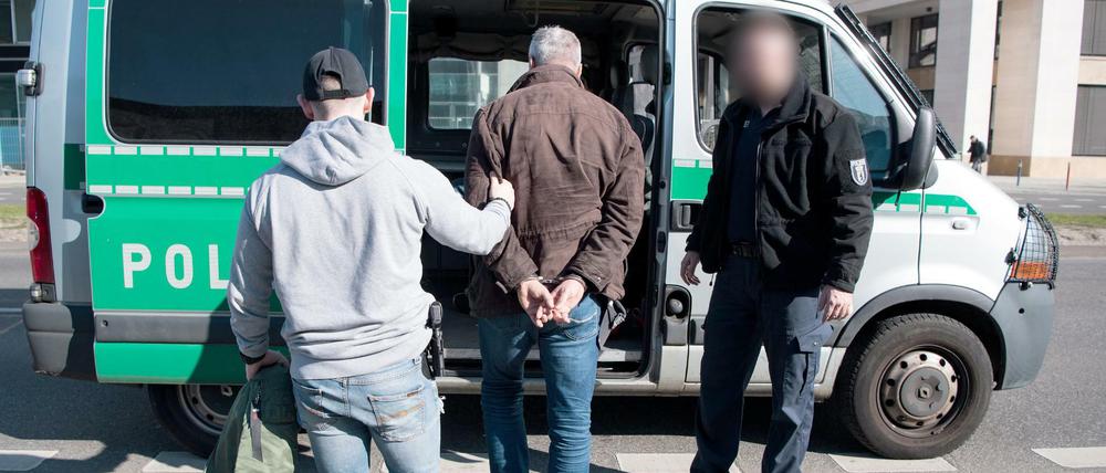 Polizeibeamte in Zivil führen einen Hütchenspieler an der East Side Gallery zu einem Polizeiwagen.