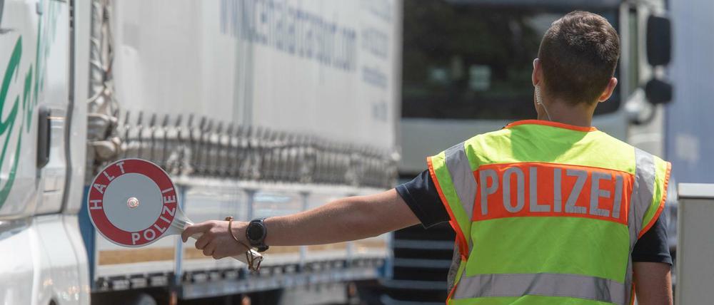Ein Polizist steht mit einer Kelle an einer Kontrollstelle der Bundespolizei auf der Autobahn 3 kurz hinter der deutsch-österreichischen Grenze.