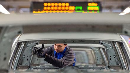 Ein Mitarbeiter schraubt im VW Werk in Wolfsburg an einem Volkswagen. 