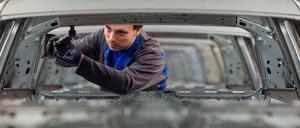 Ein Mitarbeiter schraubt im VW Werk in Wolfsburg an einem Volkswagen.