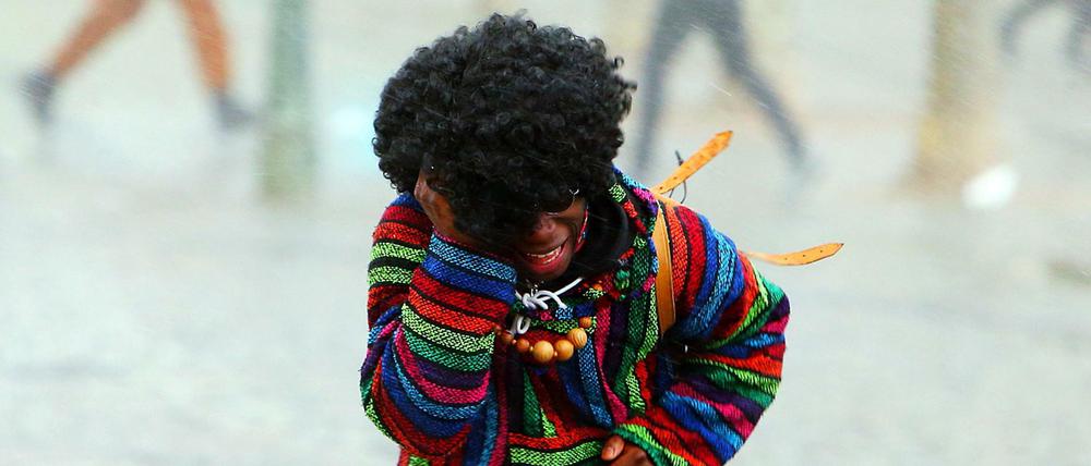 Narren flüchten am Rosenmontag 2016 in Düsseldorf vor Regen und Sturm.