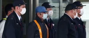 Der Automanager Carlos Ghosn (blaue Kappe) wird unter Geleit aus der Haft entlassen.
