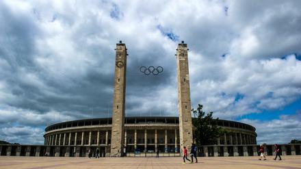 ARCHIV - Menschen gehen am 23.06.2014 in Berlin am Olympiastadion vorbei. Der DOSB gibt am 16.03. eine Empfehlung für die deutsche Bewerberstadt für die Olympischen Spiele 2024/2028 ab. Foto: Paul Zinken/dpa +++(c) dpa - Bildfunk+++ | Verwendung weltweit