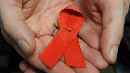Ein Mann hält eine Aids-Schleife in den Händen.