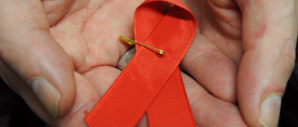 Ein Mann hält eine Aids-Schleife in den Händen.