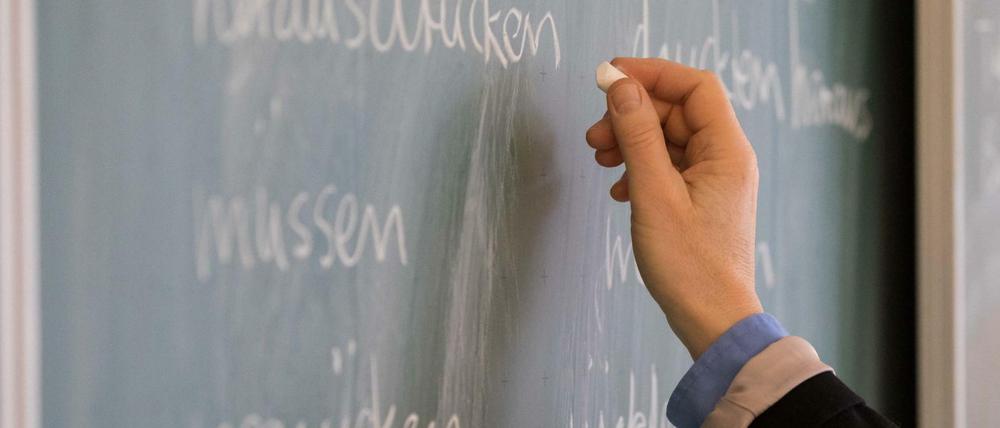 Eine Lehrerin schreibt etwas an eine Tafel.