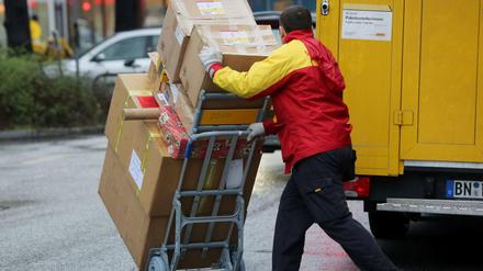 Ein Paketbote von DHL liefert Päckchen aus.