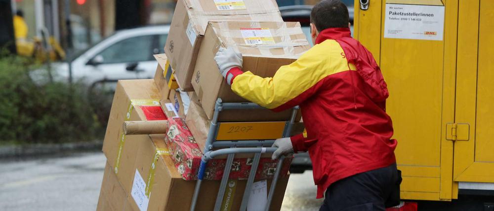 Ein Paketbote von DHL liefert Päckchen aus.
