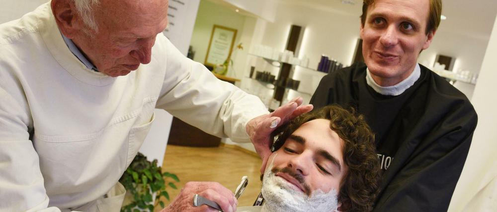 Bärte ab. Die Jesus-Darsteller der Oberammergauer Passionsspiele 2020, Rochus Rückel (vorn) und Frederik Mayet, lassen sich ein letztes Mal rasieren.