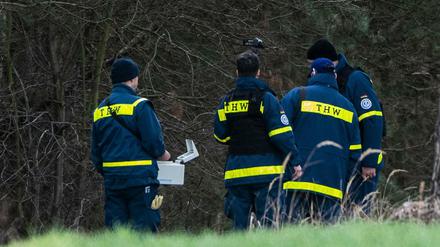 Mitglieder einer Spezialgruppe des Technischen Hilfswerks stehen mit einem Bodenradargerät in einem Wald bei Storkow.