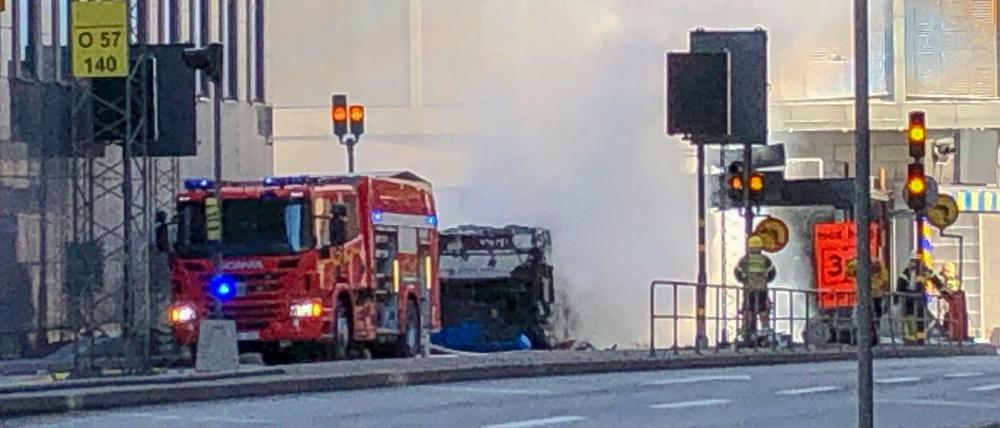 Einsatzkräfte der Feuerwehr stehen nach der Explosion eines Busses im Stadtzentrum von Stockholm. 