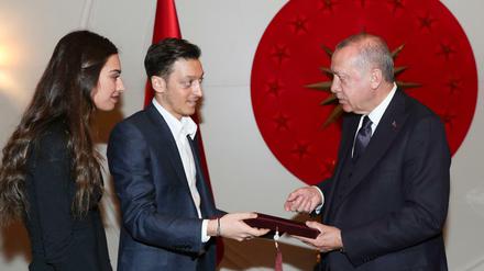  Dieses vom Presidential Press Service am 17.03.2019 zur Verfügung gestellte Foto zeigt Recep Tayyip Erdogan (r), Staatspräsident der Türkei, der nach Angaben des türkischen Präsidialamtes eine Einladungskarte für die Hochzeit des türkisch-deutschen Ex-Nationalspieler Mesut Özil (M) und seiner Verlobten Amine Gulse in Istanbul entgegen nimmt. 