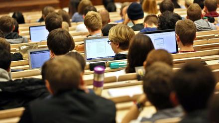 Studierende sitzen im Hörsaal vor ihren Laptops.