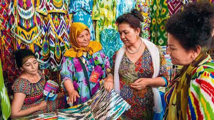 Bunte Seidenstoffe aus Usbekistan werden von Besuchern in Augenschein genommen.