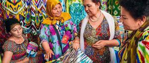Bunte Seidenstoffe aus Usbekistan werden von Besuchern in Augenschein genommen.