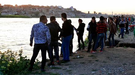 Menschen stehen am Ufer des Flusses Tigris, auf dem eine Fähre gesunken ist.