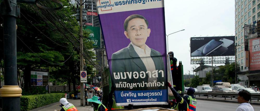 Arbeiter stapeln Wahlplakate am Straßenrand in Bangkok.