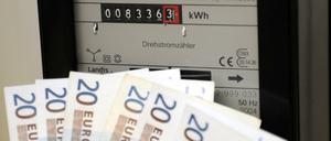Geldscheine vor einen Stromzähler gehalten. (Symbolbild)