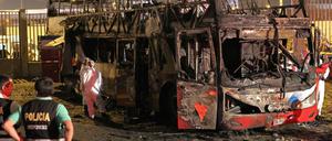 Polizisten stehen vor dem ausgebrannten Bus. 