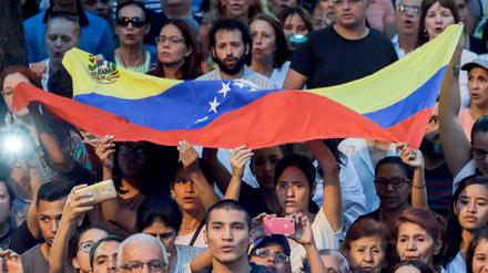 Menschen hören Venezuelas selbst ernanntem Interimspräsidenten Juan Guaido in Caracas während einer Kundgebung zu.