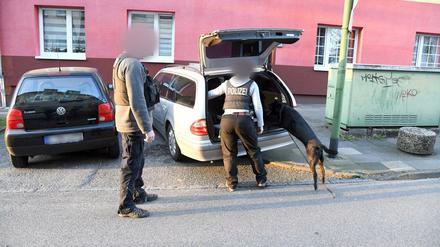 Polizisten mit einem Spürhund durchsuchen ein Auto.