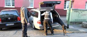Polizisten mit einem Spürhund durchsuchen ein Auto.