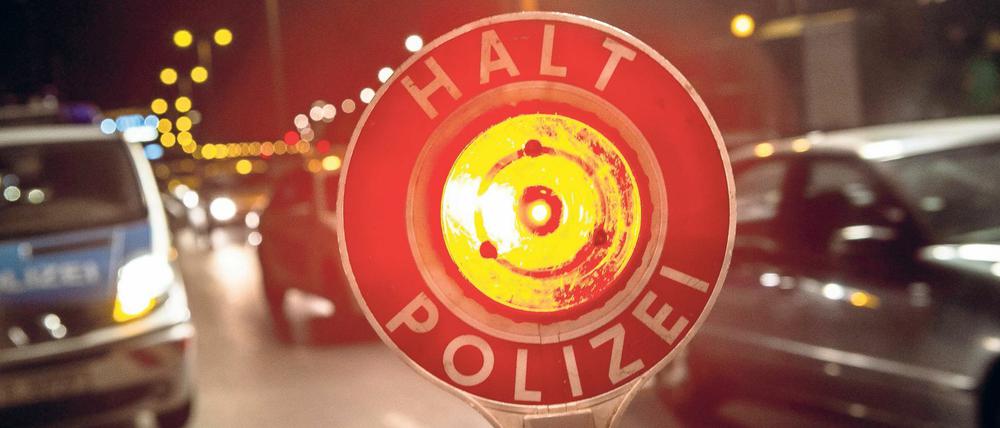 Ein Polizist stoppt mit seiner Kelle einen Pkw. (Symbolbild)