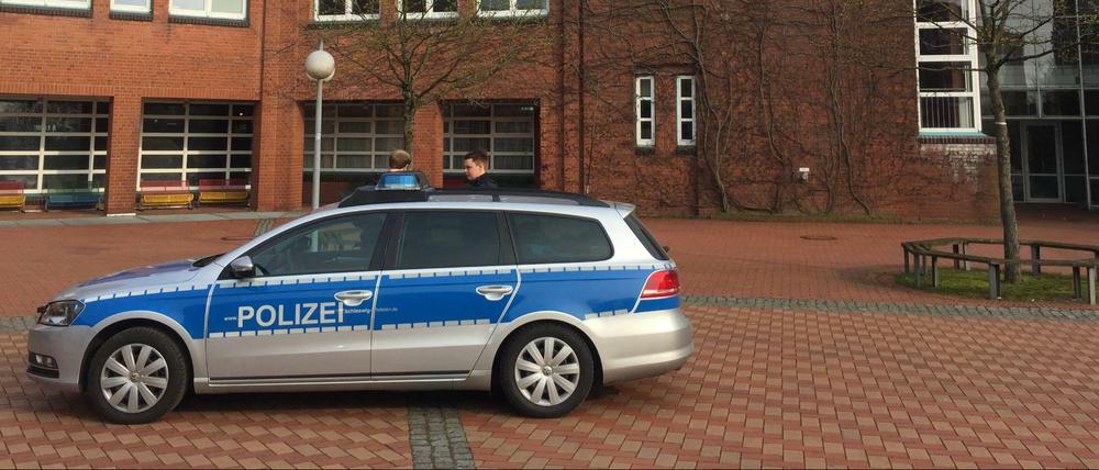 Ein Einsatzfahrzeug der Polizei und Polizeibeamte stehen während eines Einsatzes vor der Eckener Schule.