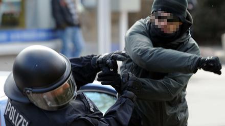 Ein gewalttätiger Demonstrant schlägt einen Polizeibeamten nieder (Archiv). 