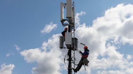 Techniker instalieren eine Antenne für das 5G Funknetz auf einem Hausdach in der schweizer Hauptstadt Bern. 