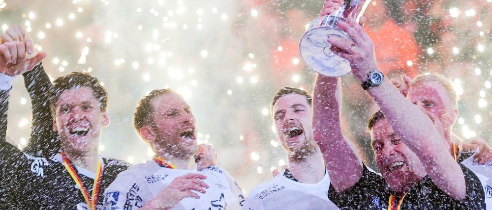 Die Kieler Mannschaft feiert mit Kiels Trainer Alfred Gislason (r) den Pokalsieg. 